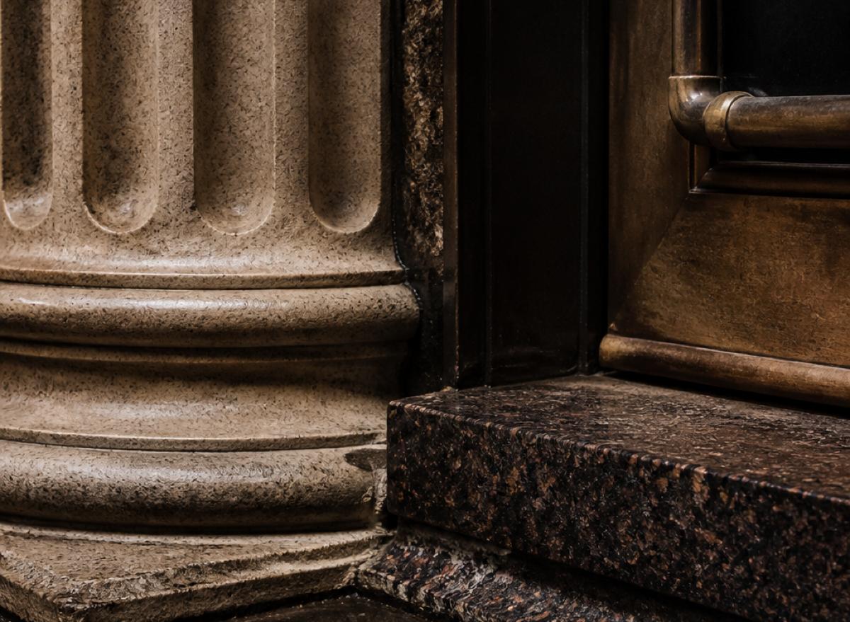 Stone column meeting a dark architectural recess — materials intersecting at a threshold