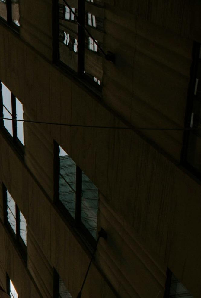 Dark stone commercial facade and window grid, looking up