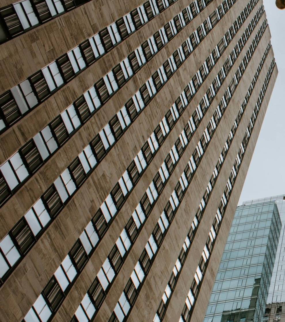 Stone institutional facade rising beside a neighbouring glass building