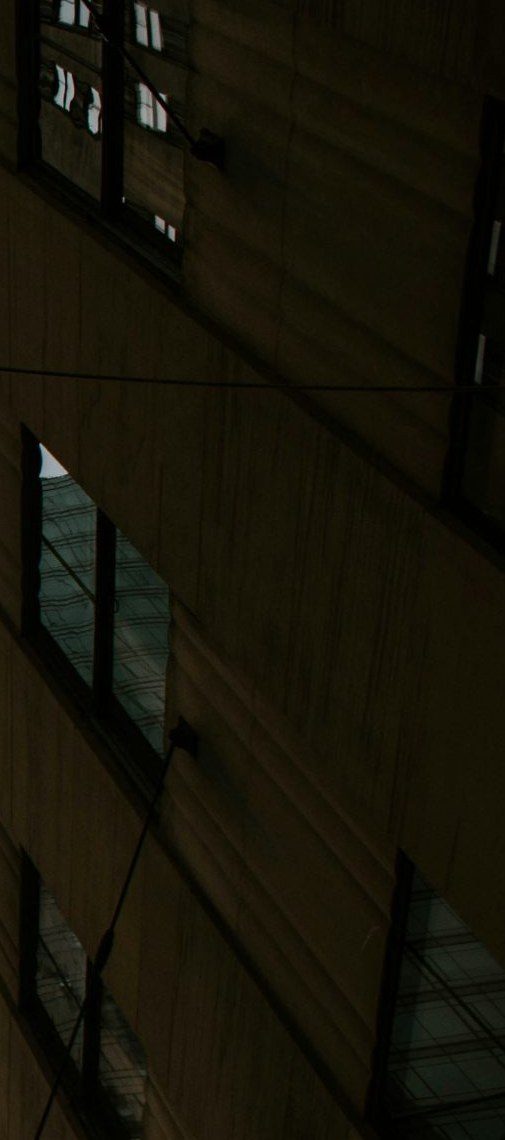 Ribbed stone facade of a commercial building with reflected office windows