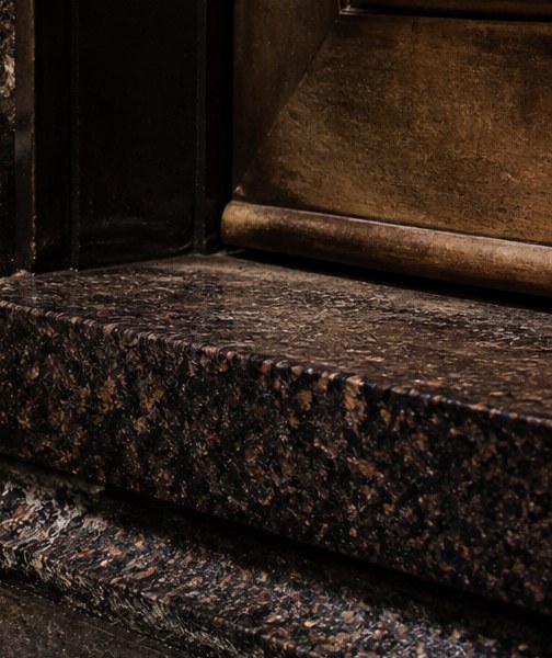 Polished granite step meeting a bronze threshold plate